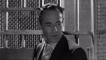 Movie still from “The Wrong Man” (1956), directed by Alfred Hitchcock – Black and white photograph of a man wearing a suit; Close Up shot, High angle