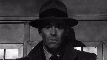 Movie still from “The Wrong Man” (1956), directed by Alfred Hitchcock – A black and white photo of a man wearing a hat; Close Up shot, Low angle