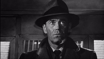 Movie still from “The Wrong Man” (1956), directed by Alfred Hitchcock – Black and white photograph of a man wearing a hat; Close Up shot, Low angle