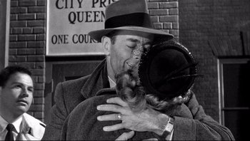 Movie still from “The Wrong Man” (1956), directed by Alfred Hitchcock – An old photo of a man and a woman kissing; Close Up shot, Over the shoulder angle