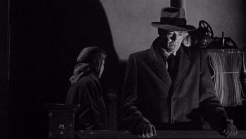 Movie still from “The Wrong Man” (1956), directed by Alfred Hitchcock – A man and a woman standing next to each other in a room; Medium shot, Low angle