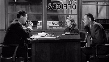 Movie still from “The Wrong Man” (1956), directed by Alfred Hitchcock – A group of people sitting at a table in front of a building; Medium shot, Over the shoulder angle