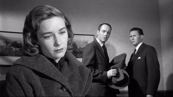 Movie still from “The Wrong Man” (1956), directed by Alfred Hitchcock – A black - and - white photo of a woman and two men; Close Up shot, Over the shoulder angle