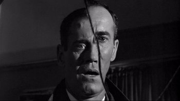 Movie still from “The Wrong Man” (1956), directed by Alfred Hitchcock – A black and white photo of a man with a knife in his mouth; Close Up shot, Over the shoulder angle