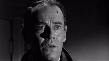 Movie still from “The Wrong Man” (1956), directed by Alfred Hitchcock – A man with a bird on his forehead is looking at the camera; Close Up shot, Low angle