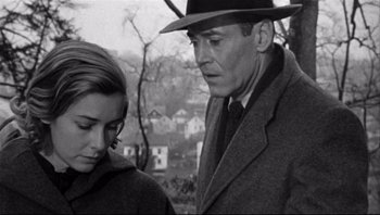 Movie still from “The Wrong Man” (1956), directed by Alfred Hitchcock – A man and a woman standing next to each other in front of some houses; Close Up shot, Over the shoulder angle