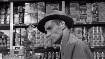 Movie still from “The Wrong Man” (1956), directed by Alfred Hitchcock – A black and white photo of a man wearing a hat; Close Up shot, Over the shoulder angle