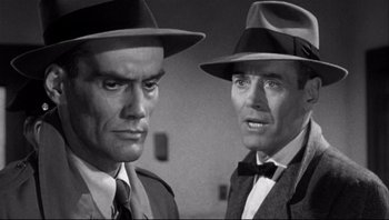 Movie still from “The Wrong Man” (1956), directed by Alfred Hitchcock – A black and white photo of two men wearing hats and ties; Close Up shot, Low angle