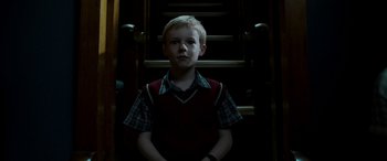 Movie still from “The Young and Prodigious T.S. Spivet” (2013), directed by Jean-Pierre Jeunet – A young boy standing in front of some stairs; Medium shot, Low angle
