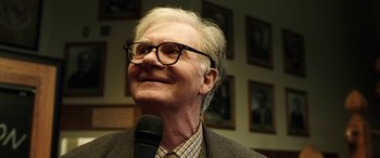 Movie still from “The Young and Prodigious T.S. Spivet” (2013), directed by Jean-Pierre Jeunet – An older man wearing glasses is holding a microphone; Close Up shot, Over the shoulder angle