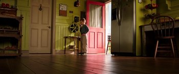 Movie still from “The Young and Prodigious T.S. Spivet” (2013), directed by Jean-Pierre Jeunet – A little boy standing in front of a red door; Wide shot, High angle