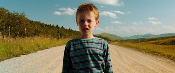 Movie still from “The Young and Prodigious T.S. Spivet” (2013), directed by Jean-Pierre Jeunet – A young boy standing on the side of a dirt road; Close Up shot, Low angle