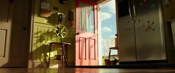 Movie still from “The Young and Prodigious T.S. Spivet” (2013), directed by Jean-Pierre Jeunet – A pink door and a fan in a room with yellow walls; Wide shot, Low angle