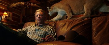 Movie still from “The Young and Prodigious T.S. Spivet” (2013), directed by Jean-Pierre Jeunet – A man sitting on a couch with a cat on the back of the couch; Medium shot, Low angle
