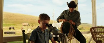 Movie still from “The Young and Prodigious T.S. Spivet” (2013), directed by Jean-Pierre Jeunet – A man and a boy looking through a microscope; Medium shot, Over the shoulder angle