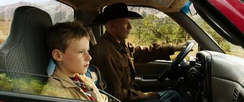 Movie still from “The Young and Prodigious T.S. Spivet” (2013), directed by Jean-Pierre Jeunet – A man and a boy in the back of a car; Medium shot, High angle