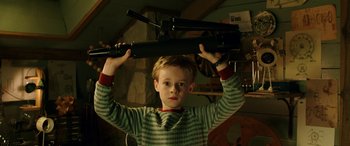 Movie still from “The Young and Prodigious T.S. Spivet” (2013), directed by Jean-Pierre Jeunet – A young boy holding up a gun in a room; Medium shot, High angle