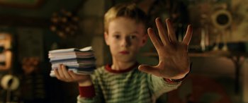 Movie still from “The Young and Prodigious T.S. Spivet” (2013), directed by Jean-Pierre Jeunet – A young boy holding a stack of papers in front of his face; Close Up shot, Over the shoulder angle