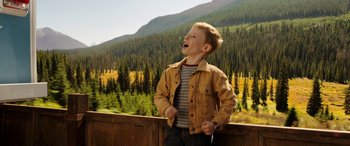Movie still from “The Young and Prodigious T.S. Spivet” (2013), directed by Jean-Pierre Jeunet – A young boy standing next to a forest; Medium shot, High angle
