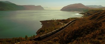 Movie still from “The Young and Prodigious T.S. Spivet” (2013), directed by Jean-Pierre Jeunet – A train traveling down tracks next to a body of water; Extreme Wide shot, High angle