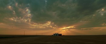 Movie still from “The Young and Prodigious T.S. Spivet” (2013), directed by Jean-Pierre Jeunet – The sun is setting over a field with a barn and other buildings; Extreme Wide shot, High angle
