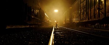 Movie still from “The Young and Prodigious T.S. Spivet” (2013), directed by Jean-Pierre Jeunet – A person is standing on the train tracks at night; Extreme Wide shot, Low angle