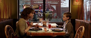 Movie still from “The Young and Prodigious T.S. Spivet” (2013), directed by Jean-Pierre Jeunet – Two people sitting at a table with plates of food in front of a window; Medium shot, High angle