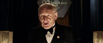 Movie still from “The Young and Prodigious T.S. Spivet” (2013), directed by Jean-Pierre Jeunet – An older man in a tuxedo is looking at the camera; Close Up shot, High angle