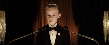 Movie still from “The Young and Prodigious T.S. Spivet” (2013), directed by Jean-Pierre Jeunet – A boy in a tuxedo standing in front of microphones; Close Up shot, Low angle