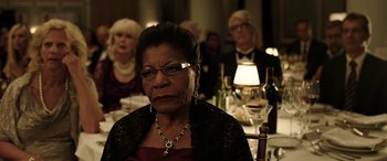 Movie still from “The Young and Prodigious T.S. Spivet” (2013), directed by Jean-Pierre Jeunet – An older woman sitting in front of a group of people at a dinner table; Close Up shot, Over the shoulder angle