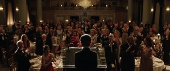 Movie still from “The Young and Prodigious T.S. Spivet” (2013), directed by Jean-Pierre Jeunet – A man sitting at a piano in front of a group of people; Wide shot, Over the shoulder angle
