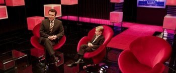 Movie still from “The Young and Prodigious T.S. Spivet” (2013), directed by Jean-Pierre Jeunet – A man and a boy sitting in a chair on a stage; Wide shot, High angle