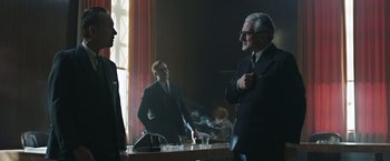 Movie still from “Their Finest” (2016), directed by Lone Scherfig – A man smoking a cigarette in front of another man; Medium shot, Over the shoulder angle