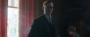 Movie still from “Their Finest” (2016), directed by Lone Scherfig – A man in a suit and tie standing in front of a curtain; Close Up shot, Low angle
