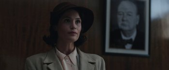 Movie still from “Their Finest” (2016), directed by Lone Scherfig – A woman wearing a brown hat and a beige jacket; Close Up shot, Low angle
