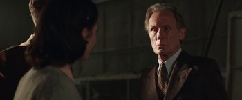Movie still from “Their Finest” (2016), directed by Lone Scherfig – An older man wearing a suit and tie talking to a young woman; Close Up shot, Over the shoulder angle