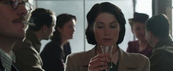 Movie still from “Their Finest” (2016), directed by Lone Scherfig – A woman holding a glass of water in her hand; Close Up shot, Over the shoulder angle