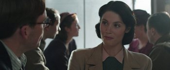 Movie still from “Their Finest” (2016), directed by Lone Scherfig – A group of people standing in a room; Close Up shot, Over the shoulder angle