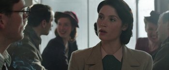 Movie still from “Their Finest” (2016), directed by Lone Scherfig – A woman in a brown jacket and a green tie; Close Up shot, Over the shoulder angle