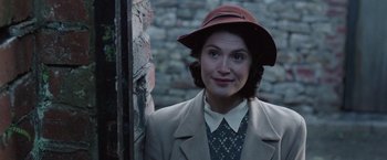 Movie still from “Their Finest” (2016), directed by Lone Scherfig – A woman wearing a brown hat and a jacket; Close Up shot, Over the shoulder angle