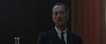 Movie still from “Their Finest” (2016), directed by Lone Scherfig – An older man wearing a suit and tie; Close Up shot, Over the shoulder angle