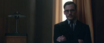 Movie still from “Their Finest” (2016), directed by Lone Scherfig – A man in a suit and tie with his arms crossed; Close Up shot, Low angle
