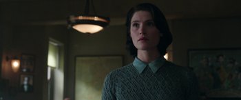 Movie still from “Their Finest” (2016), directed by Lone Scherfig – A woman standing in front of a lamp in a dimly - lit room; Close Up shot, Low angle