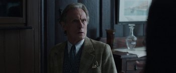 Movie still from “Their Finest” (2016), directed by Lone Scherfig – An older man wearing a suit and tie; Close Up shot, Over the shoulder angle