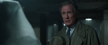 Movie still from “Their Finest” (2016), directed by Lone Scherfig – An older man wearing a tie and holding a cowboy hat; Close Up shot, Over the shoulder angle