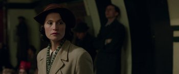 Movie still from “Their Finest” (2016), directed by Lone Scherfig – A woman wearing a hat and a coat; Close Up shot, Over the shoulder angle