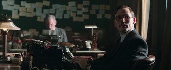 Movie still from “Their Finest” (2016), directed by Lone Scherfig – A man sitting in front of an old fashioned typewriter; Medium shot, Low angle