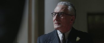 Movie still from “Their Finest” (2016), directed by Lone Scherfig – An older man wearing a suit and glasses; Close Up shot, Low angle