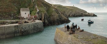 Movie still from “Their Finest” (2016), directed by Lone Scherfig – A group of people standing next to a body of water; Extreme Wide shot, High angle