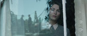 Movie still from “Their Finest” (2016), directed by Lone Scherfig – A woman looking out of a window at a tree; Close Up shot, Over the shoulder angle